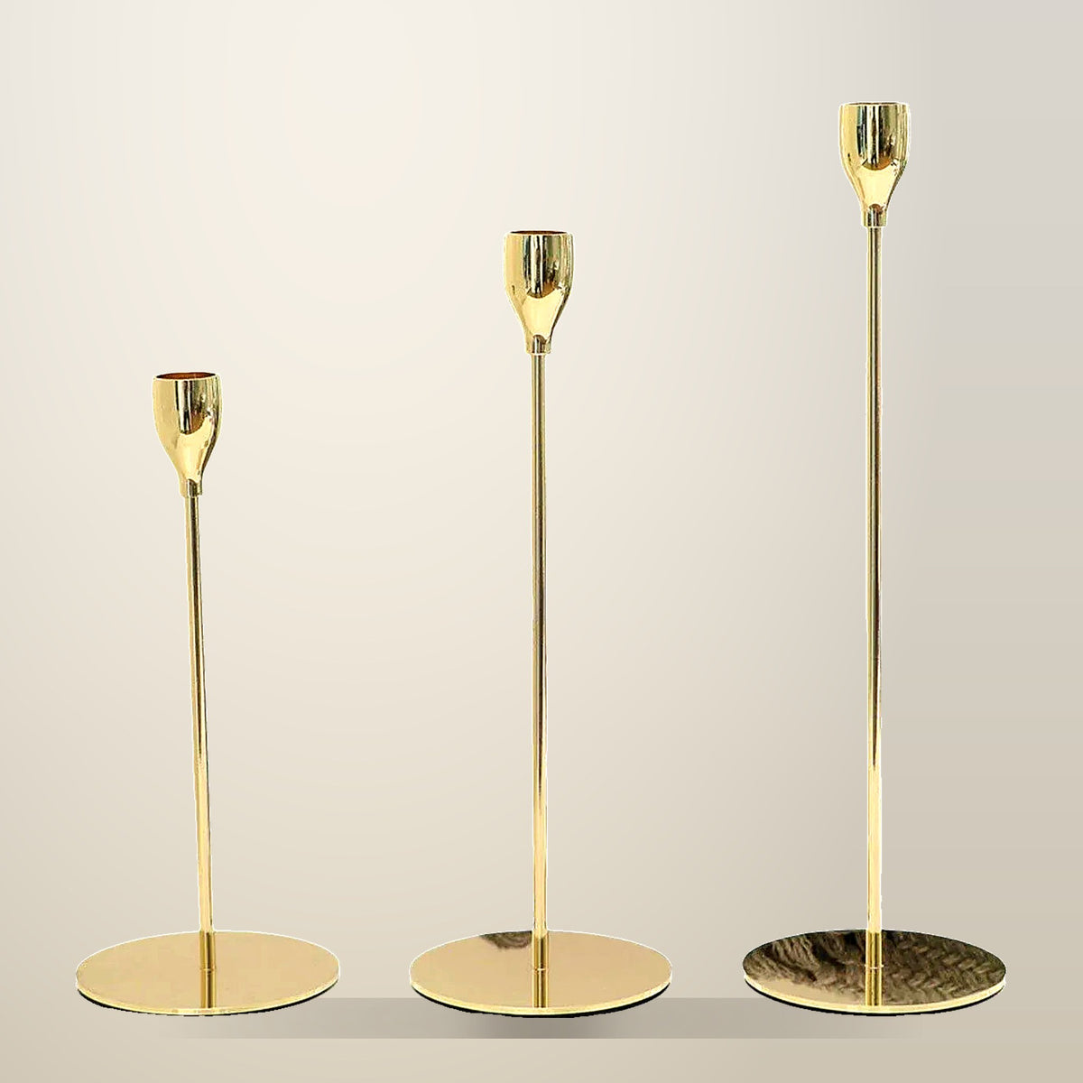 Set of 3 Metal Candlestick Holders, 22 to 33 cm, on a plain cream background